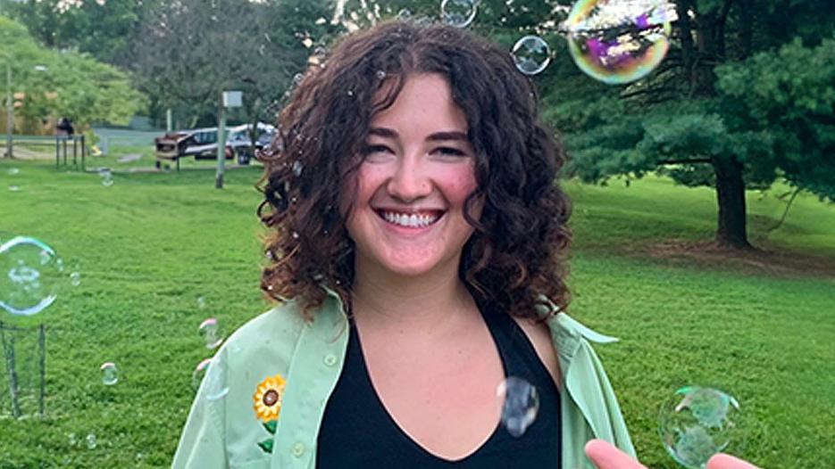 Eva smiles in an outdoor setting surrounded by bubbles